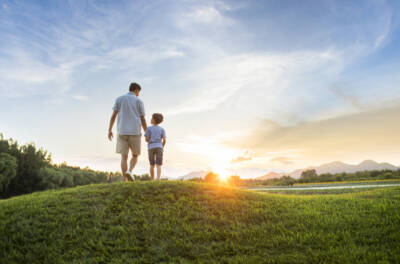 Isä ja poika kävelevät numinummella ilta-auringon laskiessa. Terve tulevaisuus. Teva.